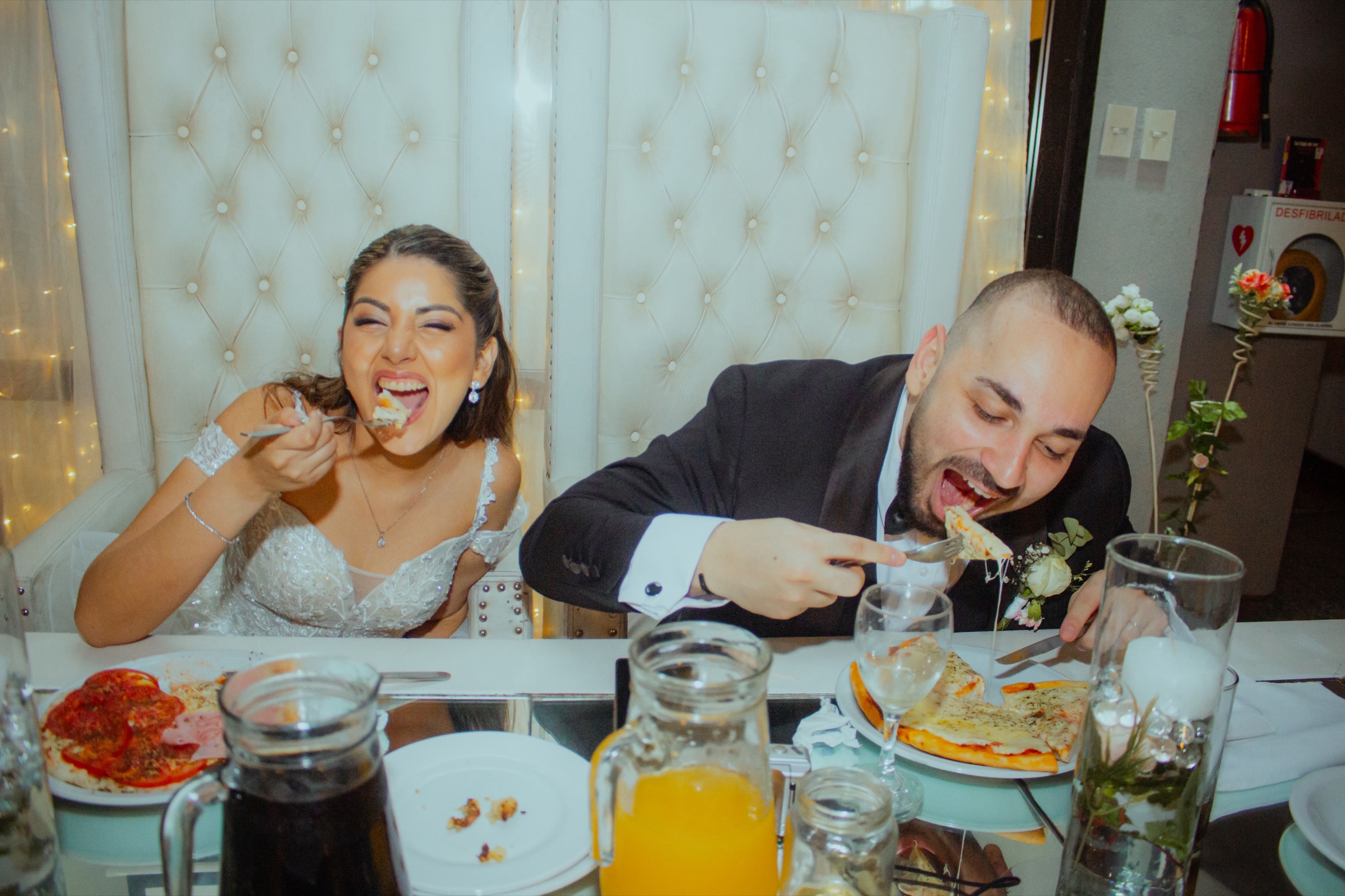 Los novios comiendo y riendo en la mesa principal